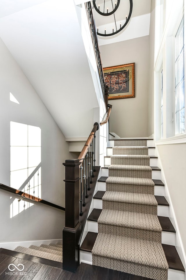 staircase featuring lofted ceiling, baseboards, and wood finished floors