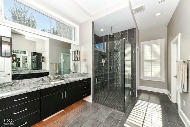 bathroom featuring visible vents, plenty of natural light, a shower stall, and vanity