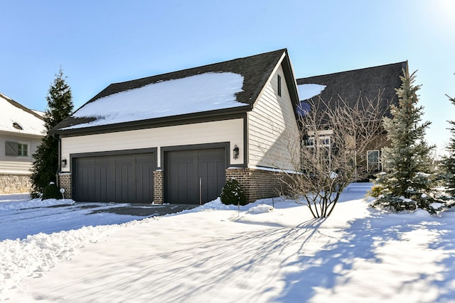 view of snowy exterior featuring a garage