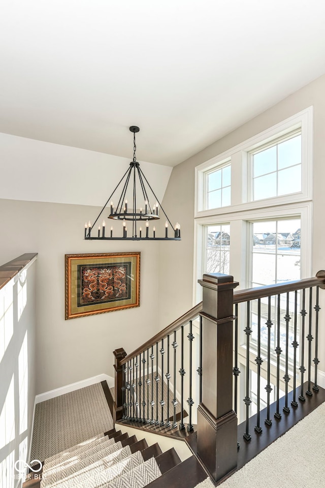 stairs featuring baseboards and a notable chandelier