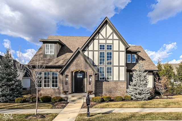 tudor home with brick siding, roof with shingles, and stucco siding