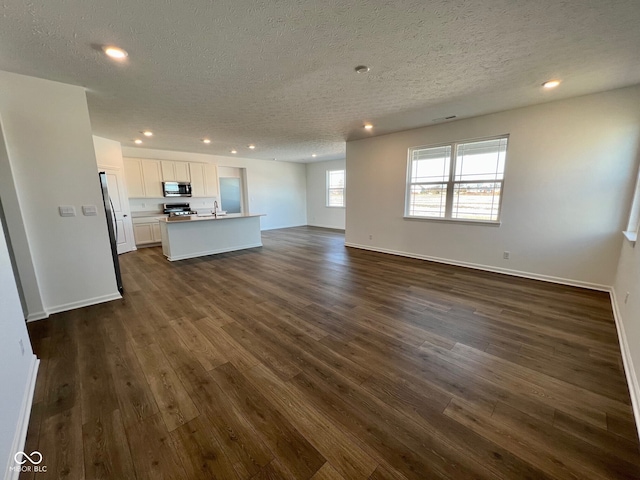 unfurnished living room with dark hardwood / wood-style floors, sink, and a textured ceiling