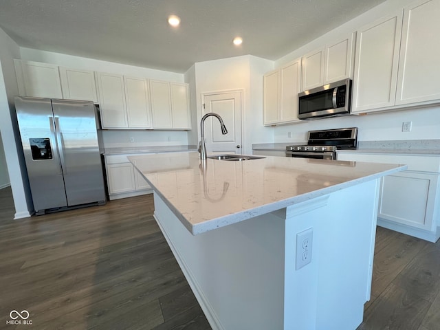 kitchen featuring stainless steel appliances, white cabinetry, and a center island with sink