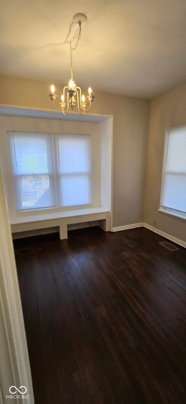 unfurnished dining area featuring wood-type flooring, a wealth of natural light, and an inviting chandelier