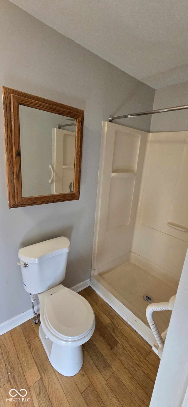 bathroom with a shower, hardwood / wood-style flooring, and toilet