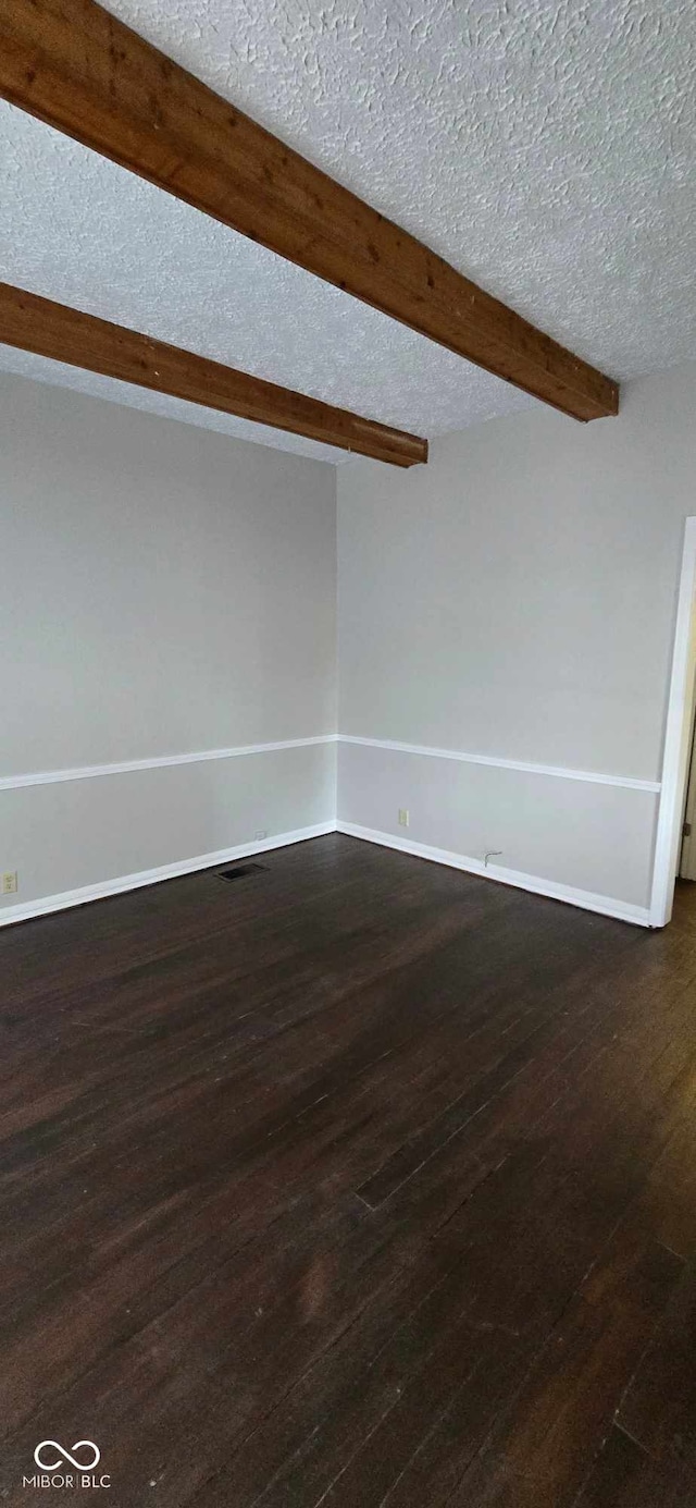 spare room with beamed ceiling, a textured ceiling, and dark hardwood / wood-style flooring