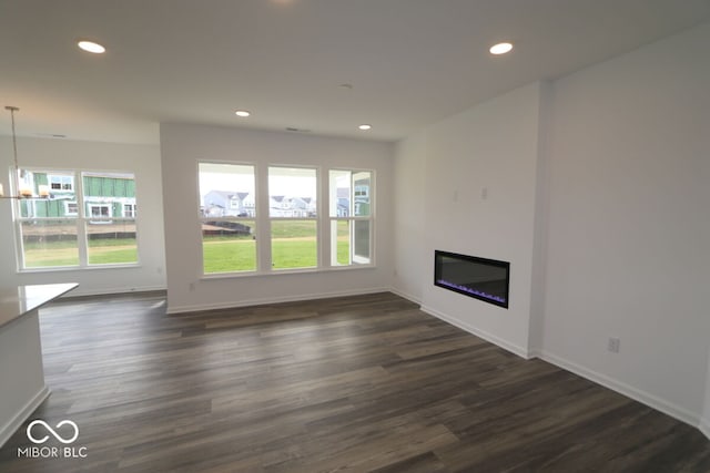 unfurnished living room with dark hardwood / wood-style flooring, a healthy amount of sunlight, and a notable chandelier