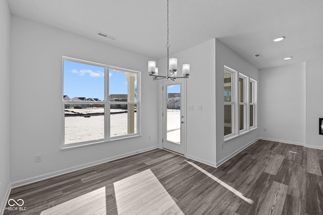 unfurnished dining area featuring an inviting chandelier and dark hardwood / wood-style floors