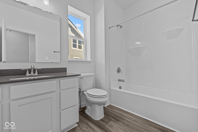 full bathroom featuring toilet, wood-type flooring, vanity, and washtub / shower combination