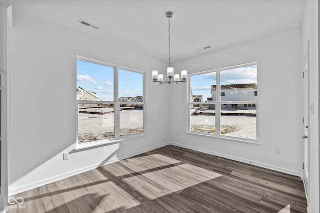 unfurnished dining area featuring a chandelier and dark hardwood / wood-style floors