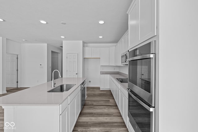 kitchen featuring appliances with stainless steel finishes, sink, white cabinetry, and a kitchen island with sink