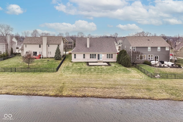 back of house with a lawn and a water view