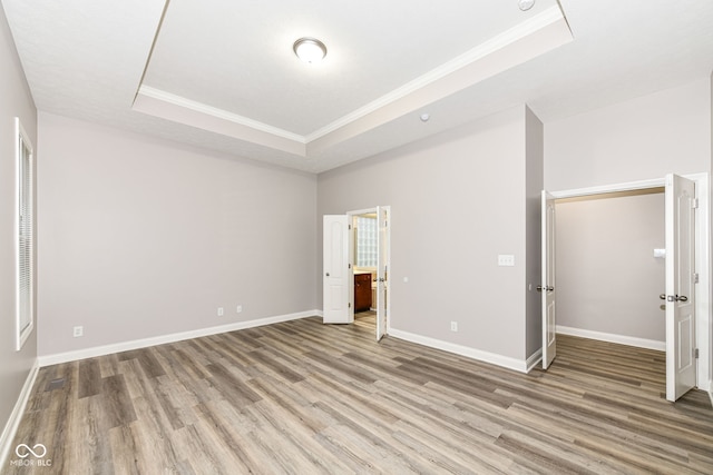 unfurnished bedroom featuring a tray ceiling, light hardwood / wood-style flooring, and ornamental molding