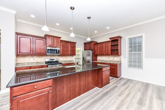 kitchen with appliances with stainless steel finishes, decorative light fixtures, a center island with sink, and light hardwood / wood-style floors