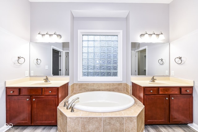 bathroom featuring tiled bath, vanity, and hardwood / wood-style flooring