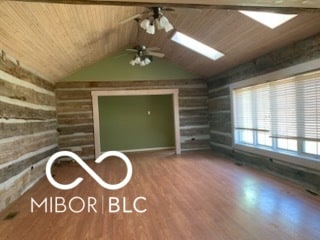 unfurnished living room with wood ceiling, log walls, wood finished floors, and ceiling fan