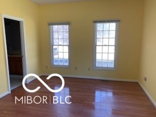 empty room featuring baseboards, wood finished floors, and a healthy amount of sunlight