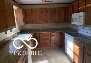 kitchen with white appliances, brown cabinetry, and a sink