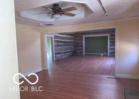 spare room with ornamental molding, wood finished floors, and baseboards
