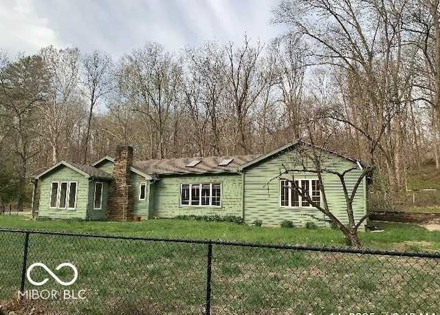 view of front of property with a front yard, a chimney, and fence