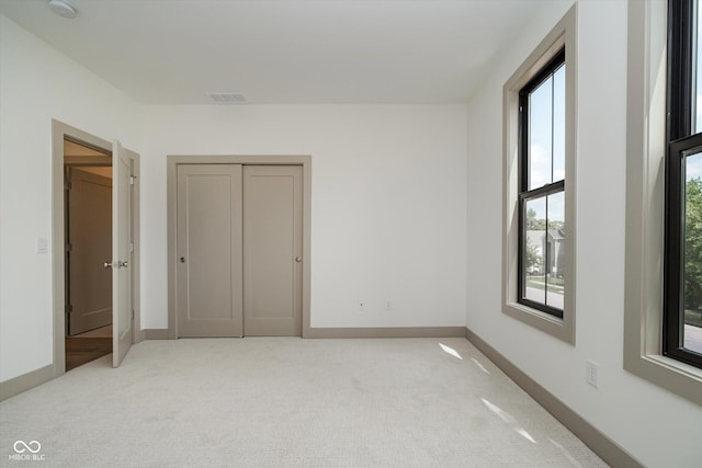 unfurnished bedroom with light colored carpet and a closet