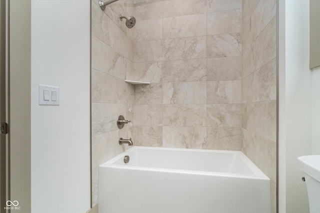 bathroom with toilet and tiled shower / bath