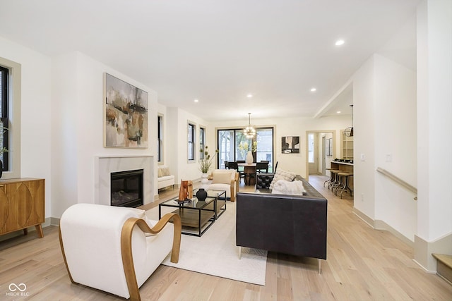 living room with light hardwood / wood-style flooring, a chandelier, and a fireplace