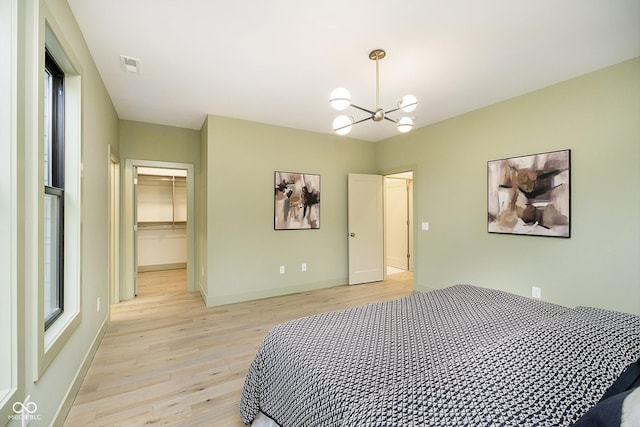 bedroom with a notable chandelier, a closet, a spacious closet, and light hardwood / wood-style floors