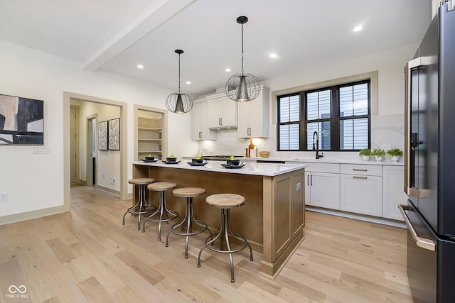 kitchen with white cabinets, stainless steel appliances, decorative light fixtures, and a center island