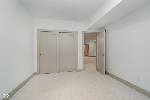 unfurnished bedroom featuring a closet and light carpet