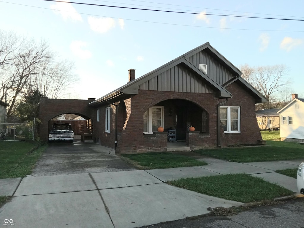 bungalow-style house featuring a porch, a front yard, and a carport