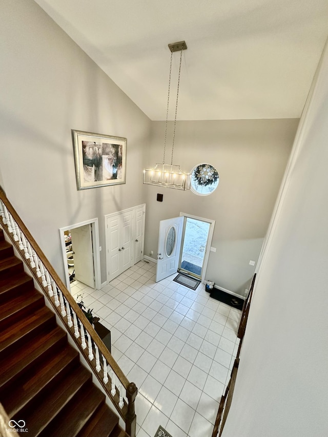 clothes washing area featuring a towering ceiling, an inviting chandelier, and light tile patterned floors