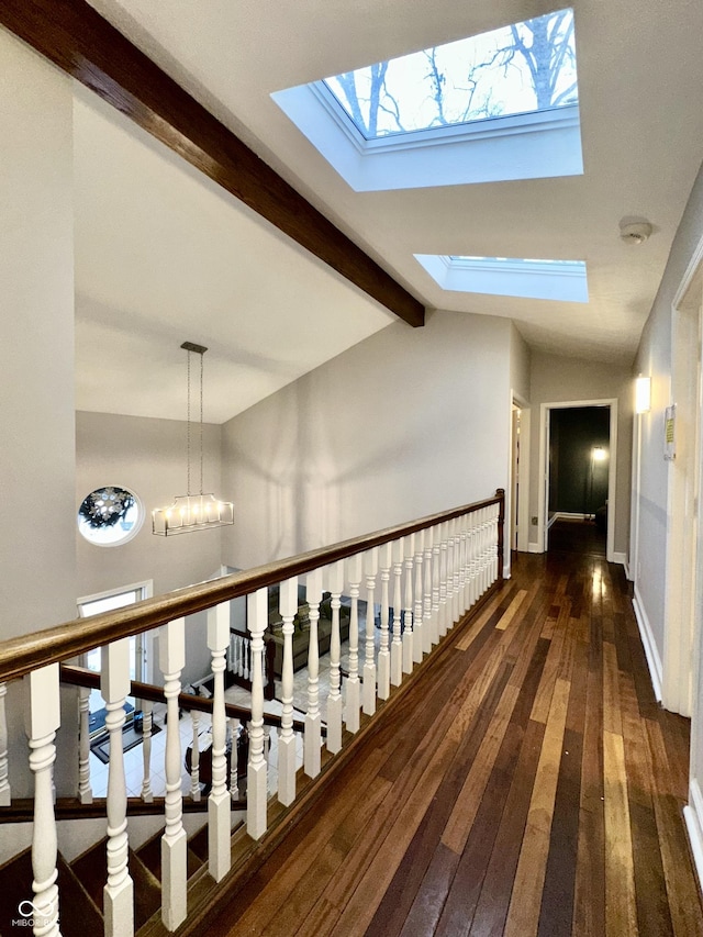 hallway featuring an inviting chandelier, lofted ceiling with skylight, and dark hardwood / wood-style floors