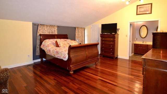 bedroom featuring lofted ceiling, dark wood-type flooring, and ensuite bathroom