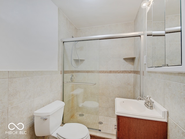 bathroom featuring vanity, toilet, tile walls, and a shower with shower door