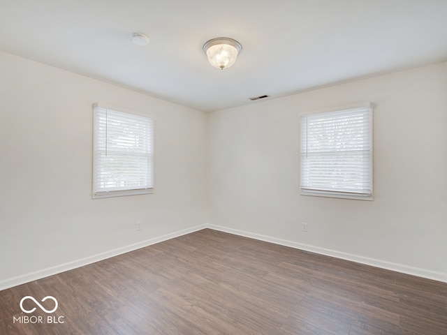 empty room with dark hardwood / wood-style floors and a healthy amount of sunlight