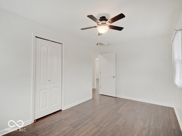 unfurnished bedroom with dark hardwood / wood-style floors, ceiling fan, and a closet