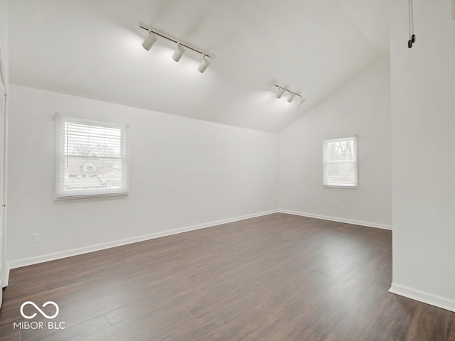 unfurnished room featuring dark hardwood / wood-style flooring, track lighting, and vaulted ceiling