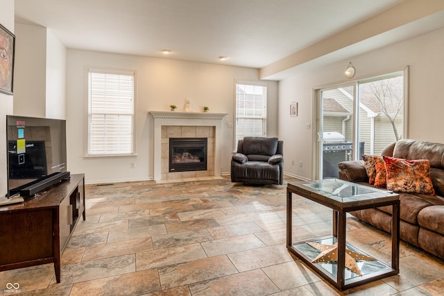 living room featuring a wealth of natural light and a tiled fireplace