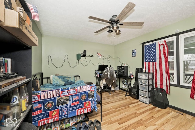 bedroom with wood-type flooring, a textured ceiling, and ceiling fan