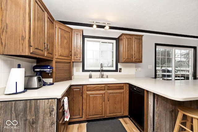 kitchen featuring crown molding, sink, light wood-type flooring, black dishwasher, and kitchen peninsula