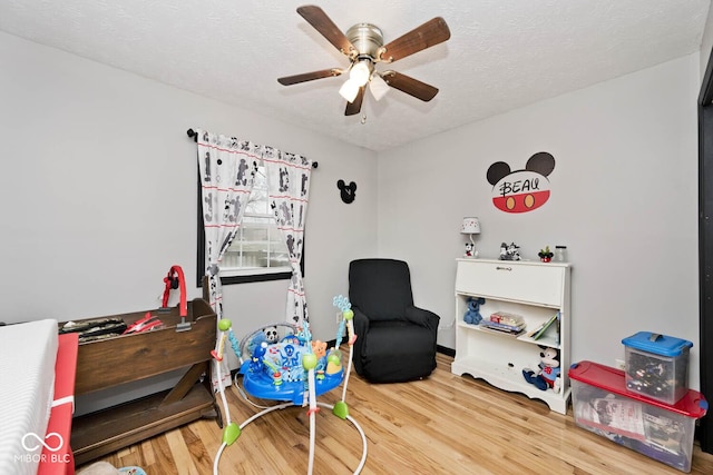 living area featuring hardwood / wood-style flooring, ceiling fan, and a textured ceiling