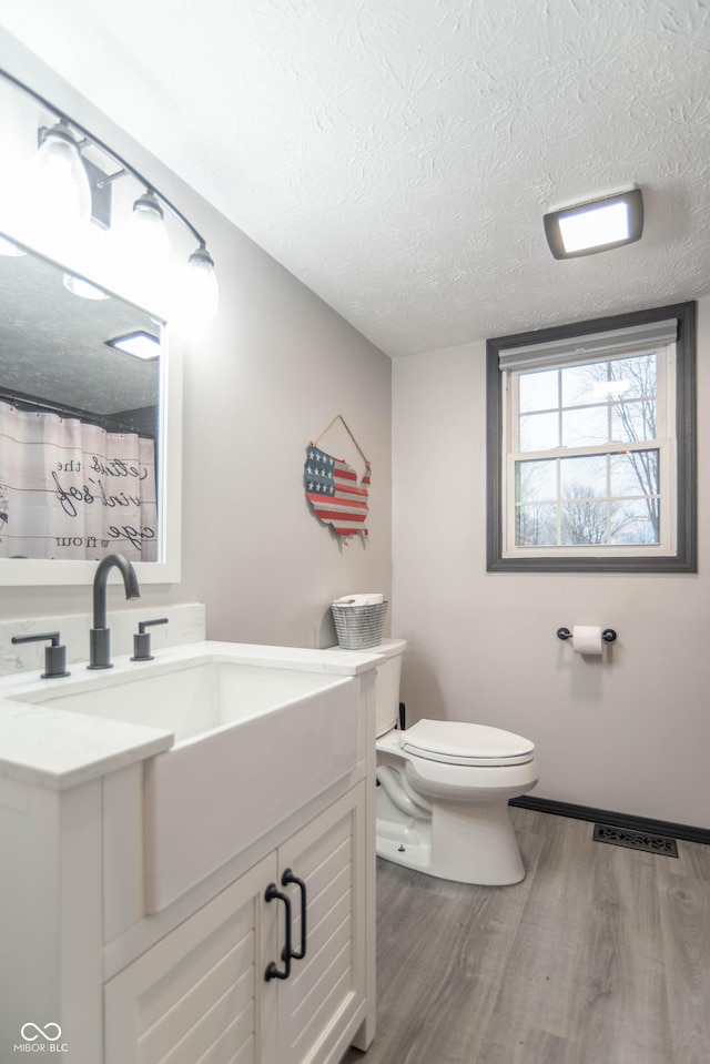 bathroom featuring a textured ceiling, toilet, vanity, and wood-type flooring