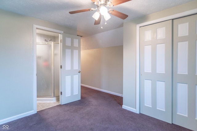 unfurnished bedroom featuring a textured ceiling, a closet, lofted ceiling, and dark carpet