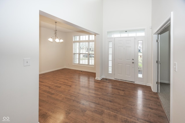 foyer with dark hardwood / wood-style flooring, an inviting chandelier, and a healthy amount of sunlight