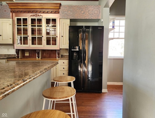 kitchen with a breakfast bar, black fridge, and dark wood-type flooring