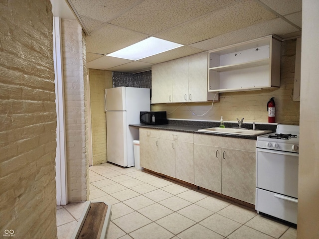 kitchen with a drop ceiling, sink, brick wall, white appliances, and light tile patterned floors