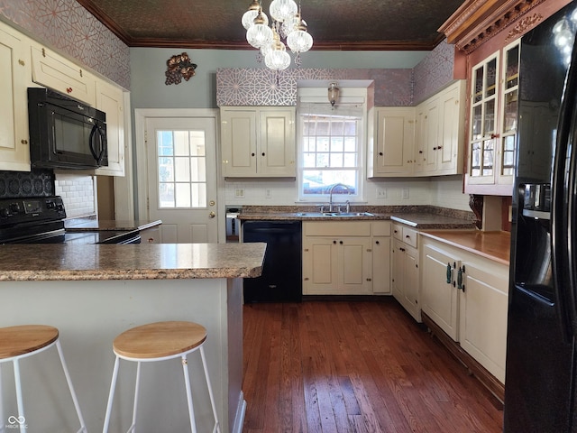 kitchen with sink, hanging light fixtures, a breakfast bar area, black appliances, and ornamental molding