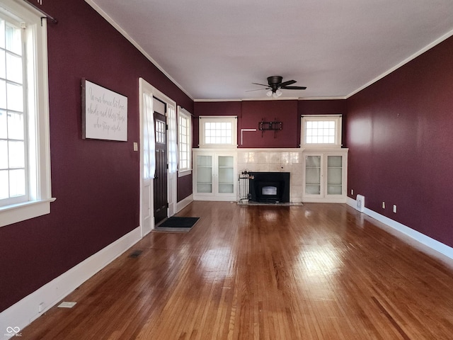 unfurnished living room featuring a healthy amount of sunlight, hardwood / wood-style flooring, ceiling fan, and crown molding