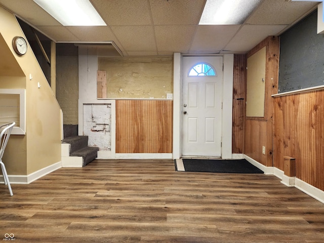 foyer with a paneled ceiling, hardwood / wood-style flooring, and wooden walls